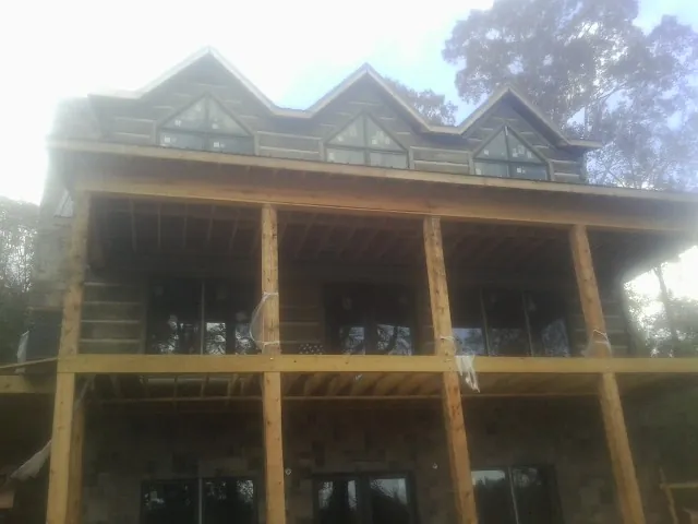 Dormers and porch framing on a large log home under construction — Roof Coating work by our crew in Eagle