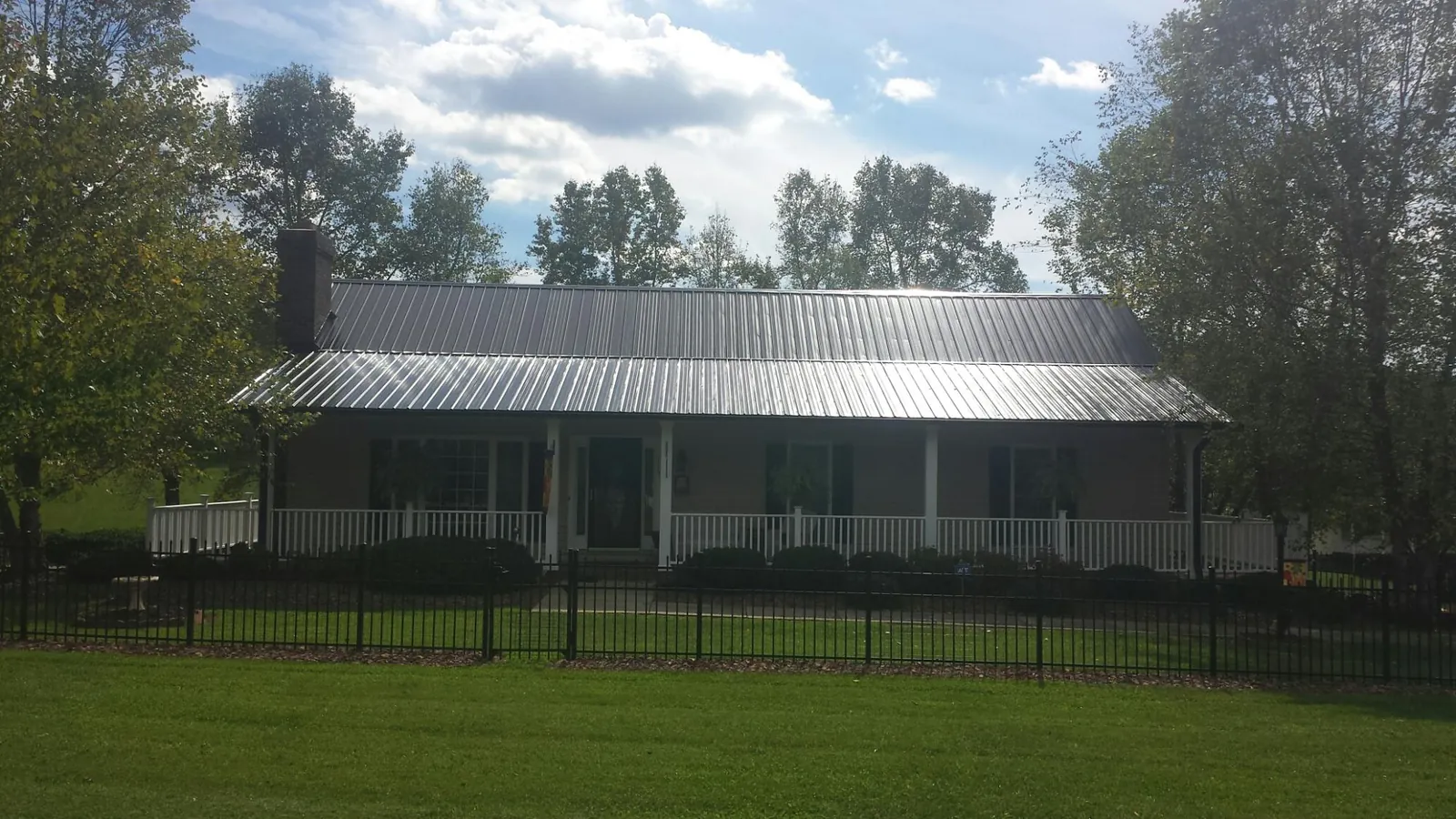 Gray metal roof on a brick ranch with a full width front porch — Gutter Guard Installation work by our crew in Eagle